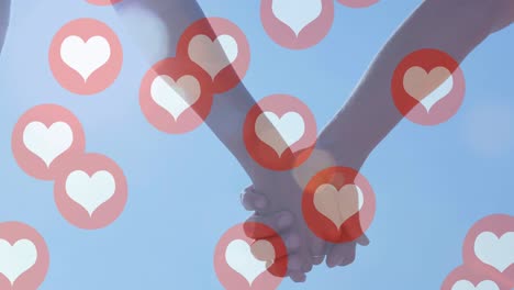 múltiples iconos de corazón flotando contra la sección media de la pareja que se toman de la mano