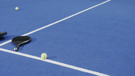 padel rackets and balls scattered on blue court, ready for play, copy space