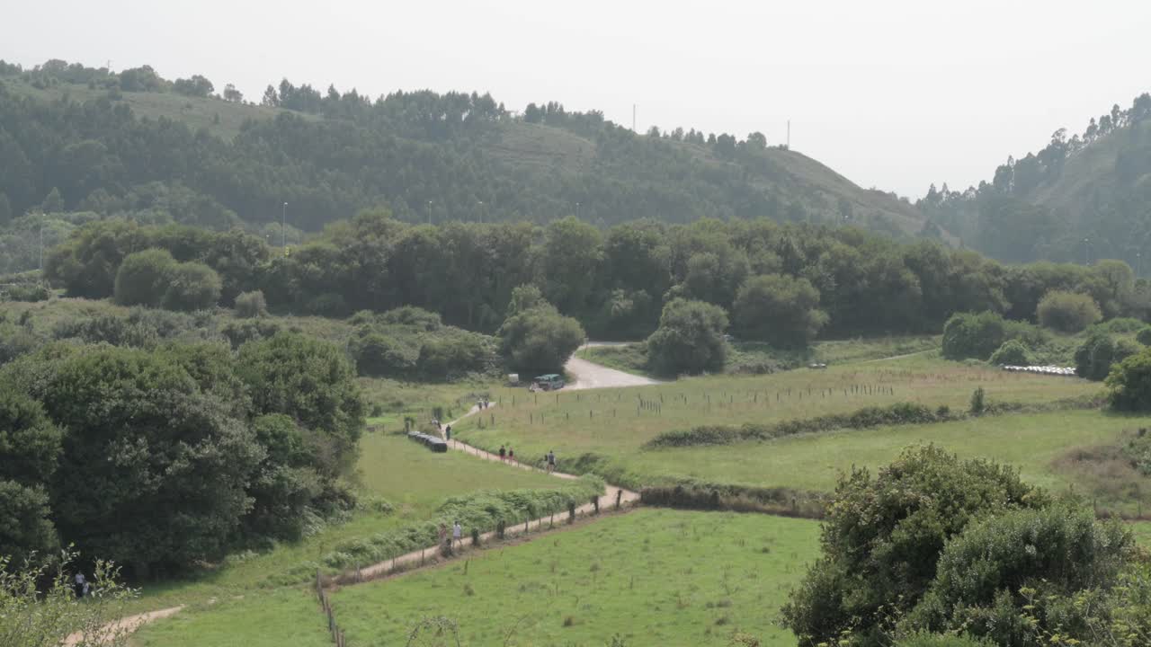 Landscape of Asturias with people walking along a path with the surroundings full of vegetation and mountains
