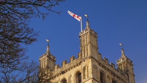 english flag flying proudly from the top of a tower against a brilliant blue sky