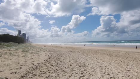 gente divirtiéndose en la playa de melbourne con grandes nubes blancas y cielo azul