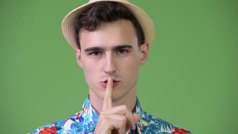 young handsome tourist man with finger on lips
