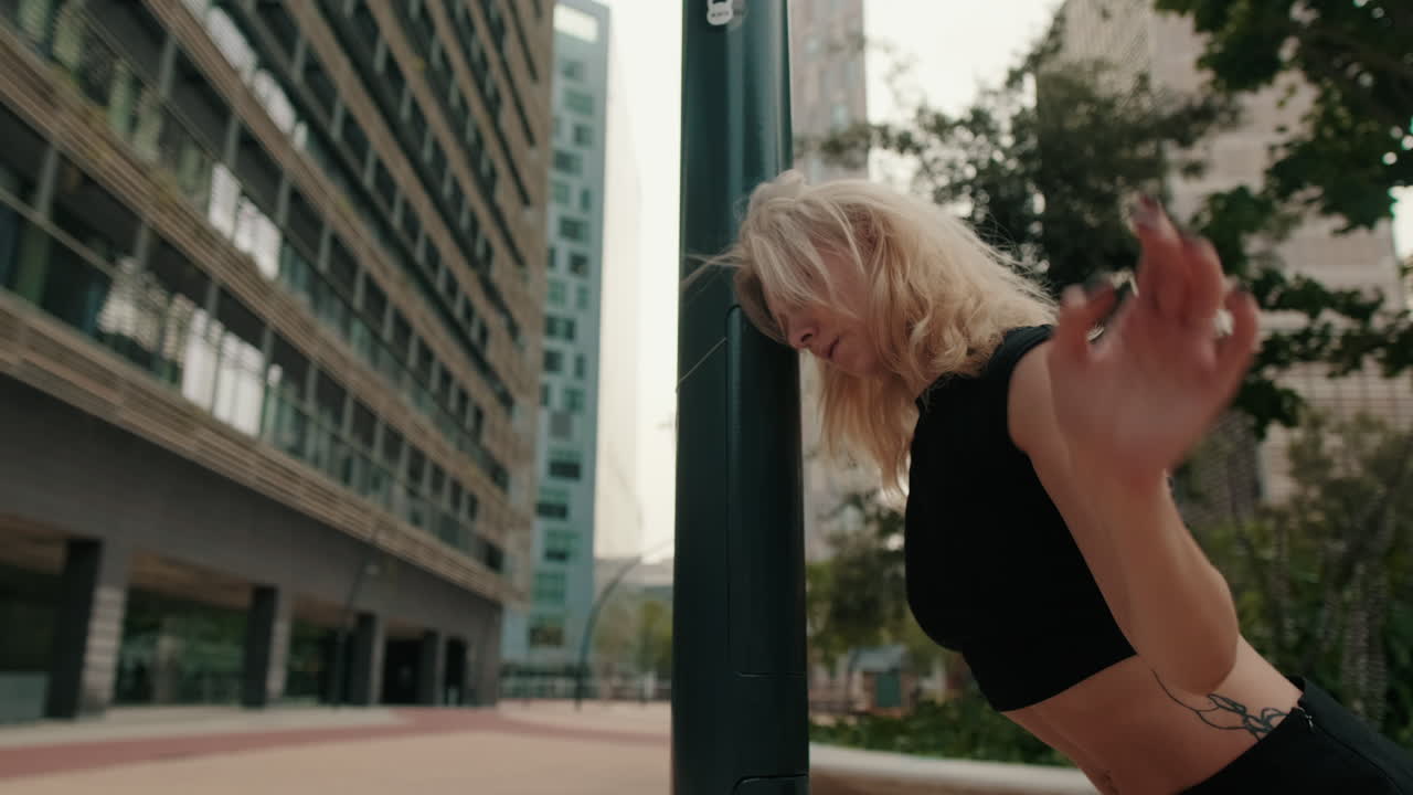 Expressive Blonde Woman Dancing in a Modern City Plaza