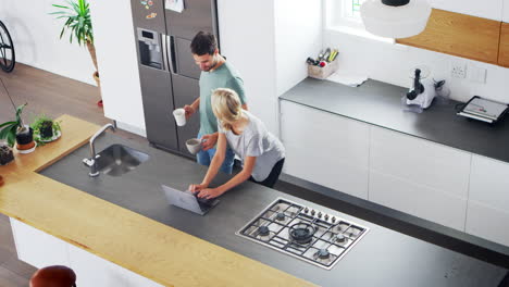 overhead view of couple looking at laptop in modern kitchen