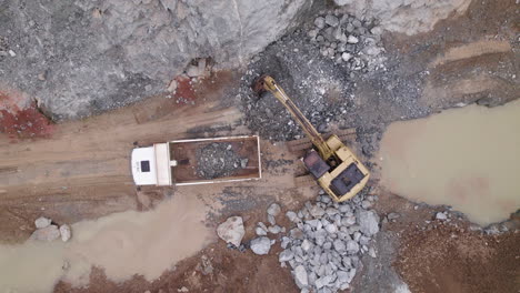 a dynamic drone shot of a excavator which empties its yield into a mining truck