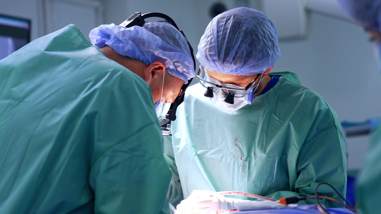 Medici uomini con occhialini chirurgici concentrati sull'operazione. Chirurghi impegnati usano strumenti medici moderni.