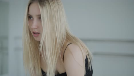 fit girl in black clothes performing contemporary. female dancer shows flowing motions, body and hands waves at white room. modern ballet dance choreography. young woman is moving smoothly