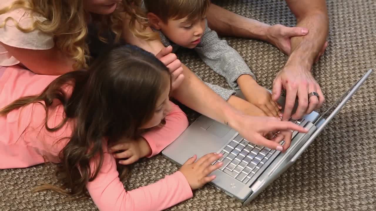 familia acostada en el suelo usando una computadora portátil