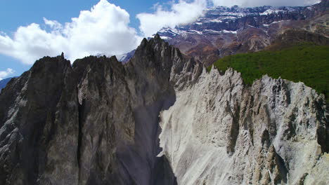 Drohnenaufnahme-Von-Berggipfeln-Des-Schlammigen-Berges-In-Manang-Nepal,-Umgeben-Von-Landschaften-Und-Hügeln-Unter-Wolkenverhangenem-Blauen-Himmel