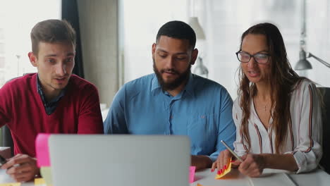 Smiling-managers-discussing-business-issues-through-laptop.