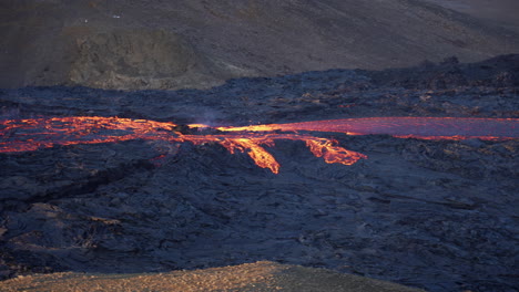 flowing lava at eruption site of volcano in geldingadalir valley near fagradalsfjall mountain, reykjanes peninsula, southwest iceland - wide shot