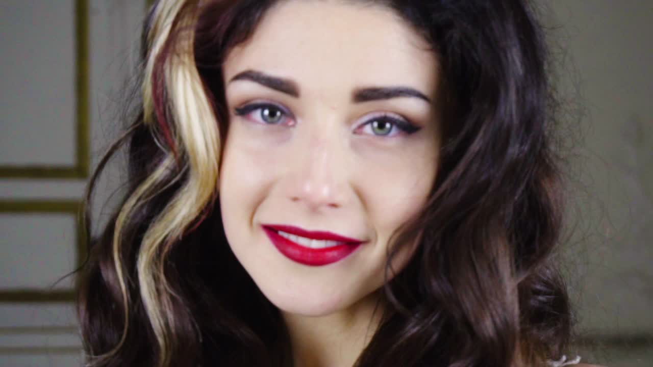 joven mujer morena con labios rojos mira a la cámara