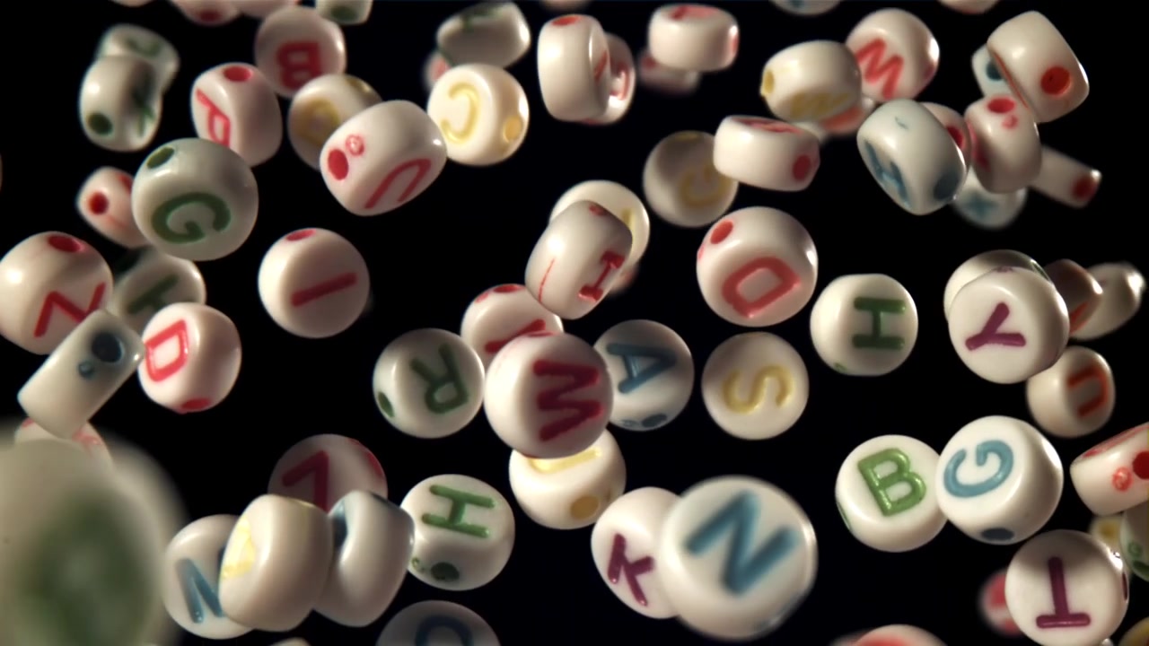 Perline colorate con lettere dell'alfabeto che cadono al rallentatore