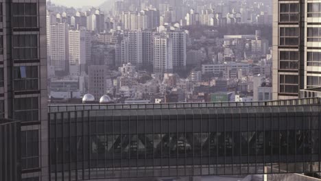 seoul, korea office worker walks through skyscraper skywalk over modern city seoul high-rise corporate skyline with apartments in background