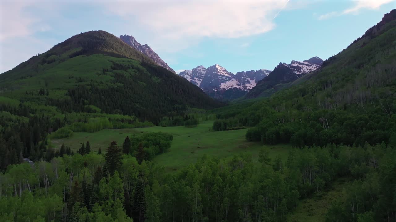 Maroon Bells Wilderness valley Elk Range Rocky Mountains Colorado aerial drone North Maroon Pyramid Peak 14er sunset spring summer blue sky clouds Aspen Snowmass White River Forest left motion