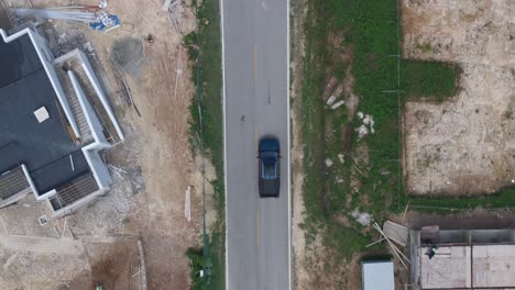 top-down tracking shot of a pickup truck driving along a dirt road at a construction site