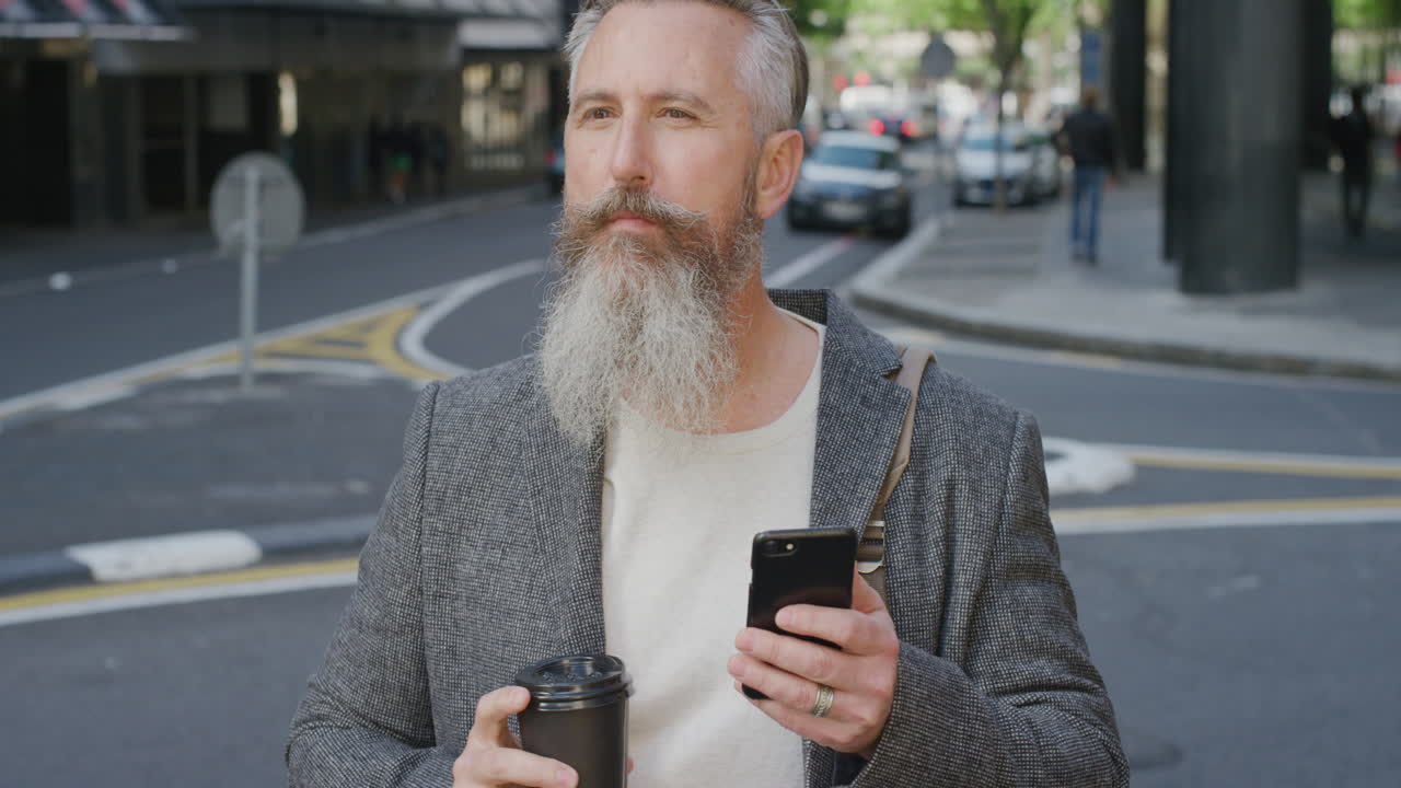 retrato de un hombre de negocios exitoso usando un teléfono inteligente enviando mensajes de texto comprobando mensajes bebiendo café en la calle de la ciudad esperando