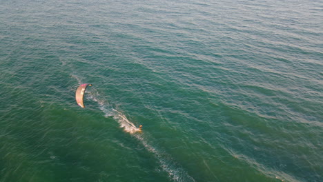 vista aerea dei kitesurfer che navigano in mezzo al mare durante la luce del tramonto, movimento della fotocamera inclinabile verso l'alto