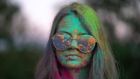 portrait of woman standing being covered in coloured powder at holi festival.