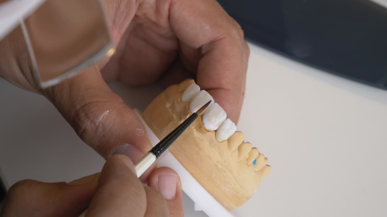 Artisan refining dental prosthetics with precision tool close up