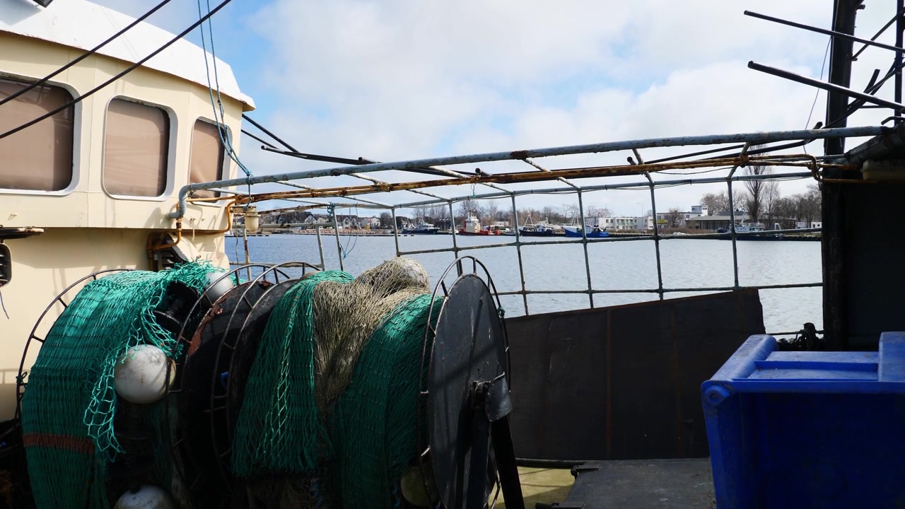 Statische Ansicht des Decks eines Fischerboots im Hafen von Jastarnia, Polen, das traditionelle maritime Details vor einer malerischen Hafenkulisse zeigt