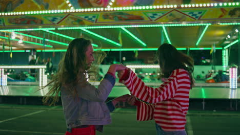 mejores amigas bailando juntas en el parque de atracciones. chicas alegres divirtiéndose