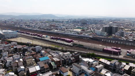 aerial view of cityscape and shinkansen arriving to kyoto train station in japan - drone shot