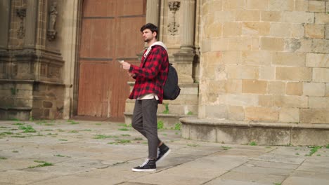 Hipster-tourist-examining-map-near-old-building