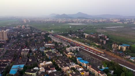 long train traveling in railroad along vasai city in mumbai, india