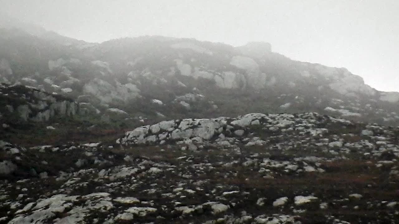 Misty rain floating across rugged rocky mountain slopes on top of Holyhead mountain North Wales