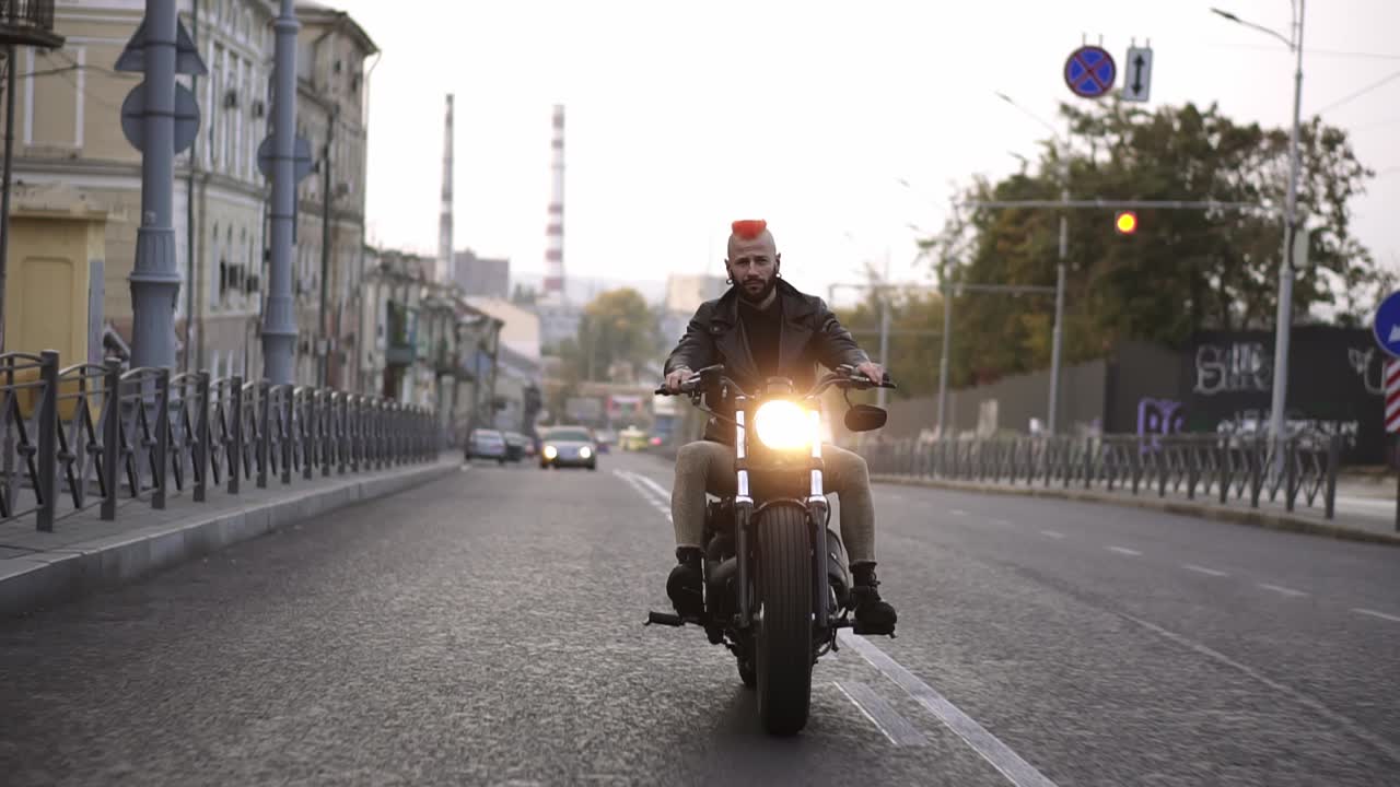 Stylish man with orange iroquois rides a bike in the city