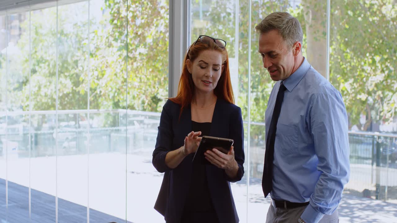 Forretningskolleger diskuterer med en digital tablet 4K.