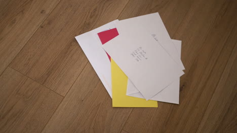 a pile of unopened letters in envelopes on a wooden floor