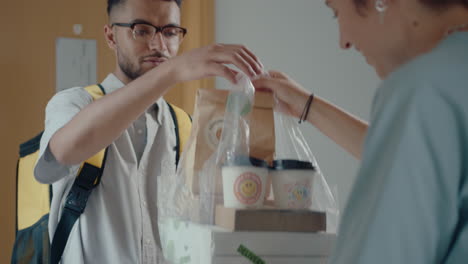 courier delivering food and drinks to female customer at home