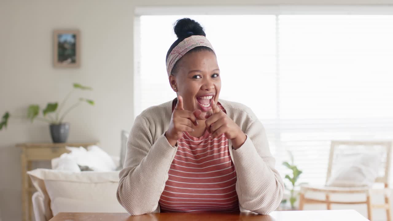 Happy unaltered african american woman sitting at table having video call, in slow motion