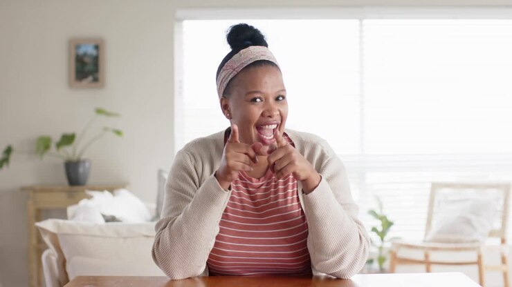 Happy unaltered african american woman sitting at table having video call, in slow motion
