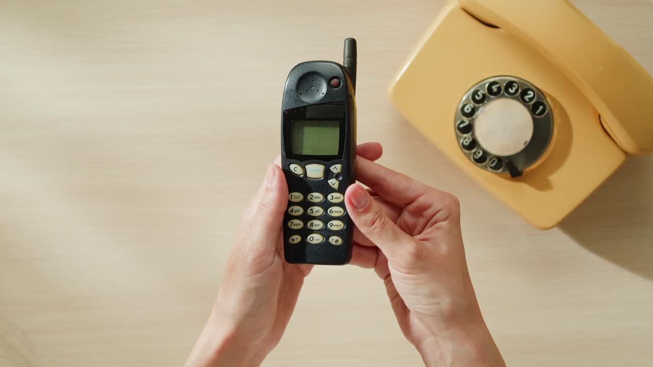 Utilizzo di un cellulare vintage accanto a un telefono a disco