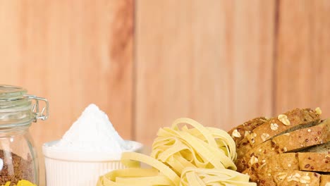 a variety of grains, pasta, and bread displayed on a wooden background with warm lighting