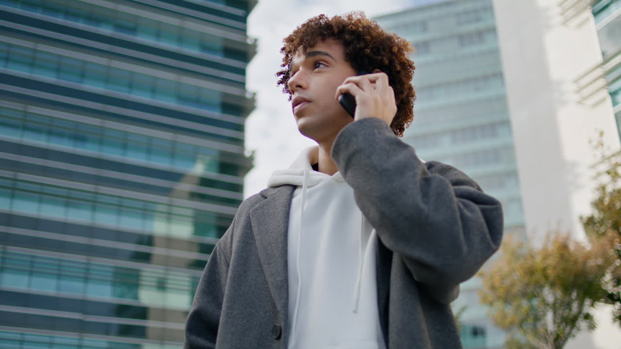 Calling teen waiting at business district close up. Serious guy looking around