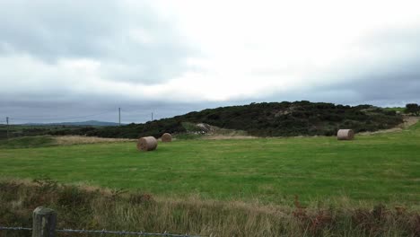 pradera agrícola rural con pacas de heno de paja enrollada en tierras de cultivo británicas nubladas abiertas