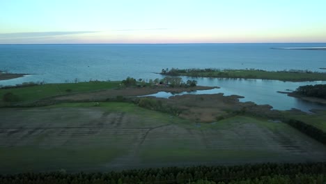 dusky sunrise over farmland and water