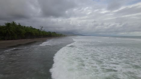 Muñeca-Aérea-Sobre-Olas-Espumosas-Golpeando-La-Arena-Cerca-De-La-Densa-Jungla-En-Un-Día-Nublado-En-La-Playa-Dominicalito,-Costa-Rica