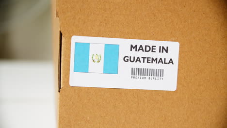 hands applying made in guatemala flag label on a shipping cardboard box with products