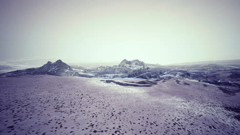 snowy mountain landscape with fog covering rocky peaks during winter