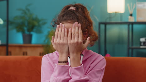 school girl playing hide and seek peekaboo game laughing hiding opening her face covering eyes