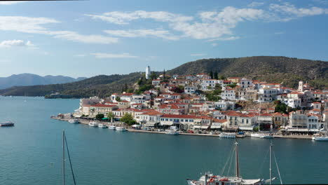 flying towards waterfront houses in poros island with boats in the sea in greece