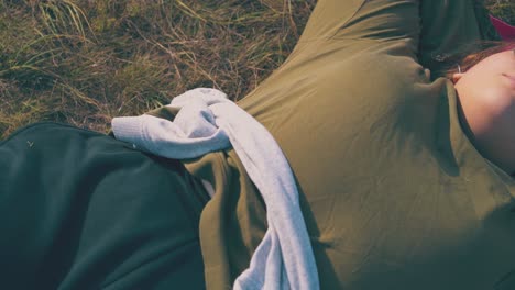 overweight-girl-with-sunglasses-rests-on-grass-at-campsite