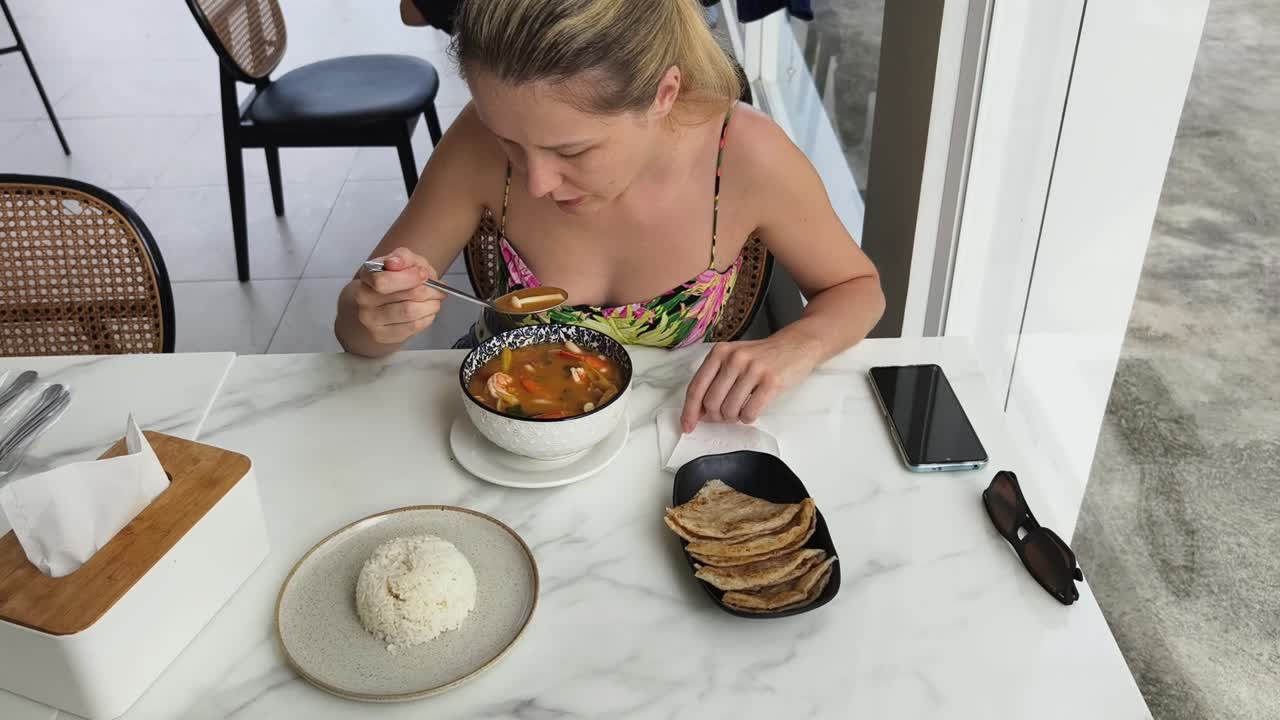 mujer disfrutando de una comida de sopa tom yum en un restaurante