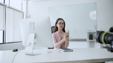 A focused businesswoman demonstrates wellness techniques during a virtual meeting in her contemporary office.