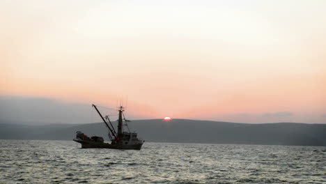 Zwei-Boote-Sitzen-Im-Wasser,-Während-Die-Sonne-über-Den-Bergen-Untergeht